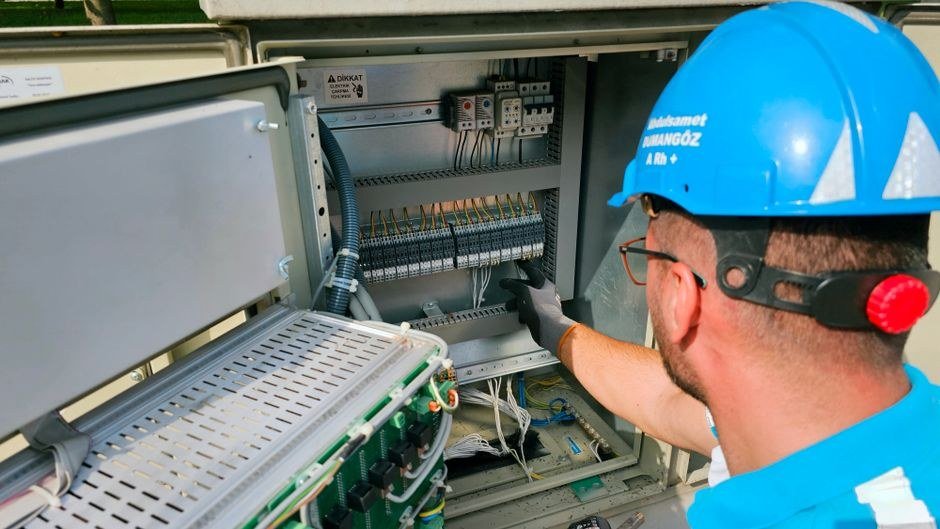 Master electrician in a hard hat wiring an industrial distribution board